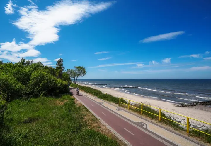 Ścieżka rowerowa nad Bałtykiem, plaża i morze w słoneczny dzień.