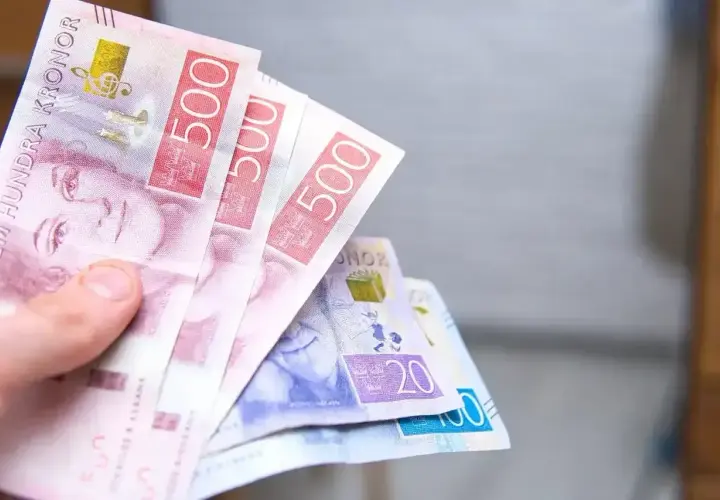 Dłoń trzyma banknoty 500 koron szwedzkich. To właśnie jaka waluta jest w Szwecji.