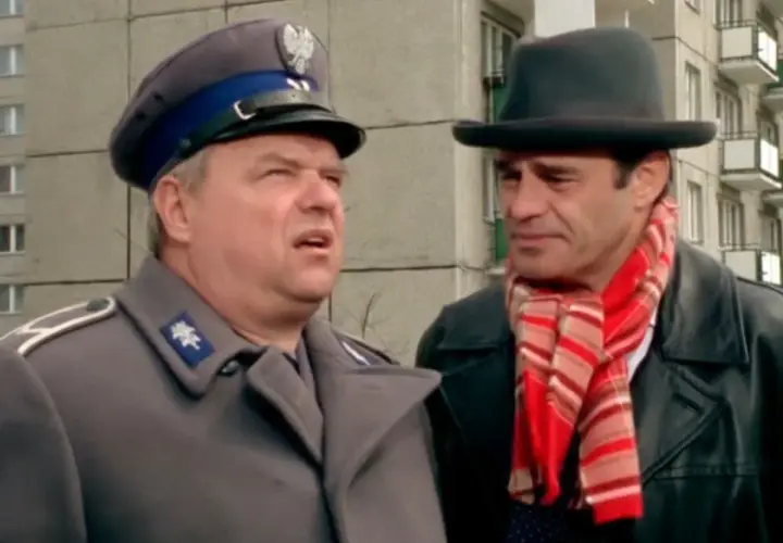 Dwóch mężczyzn, jeden w mundurze milicyjnym, drugi w kapeluszu i szaliku, w kadrze z kultowych bareja filmów.