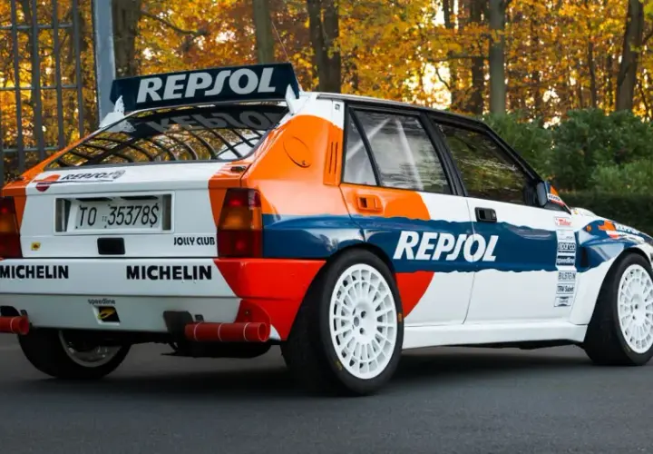 Ikoniczna Lancia Delta Integrale w barwach Repsol, z białymi felgami i naklejkami Michelin, gotowa do rajdu.
