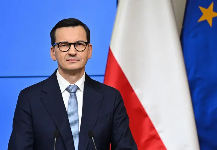 Mateusz Morawiecki w okularach, obok flagi Polski i UE. Jego rządzenie trwa od 2017 roku, kiedy to zastąpił Beatę Szydło.