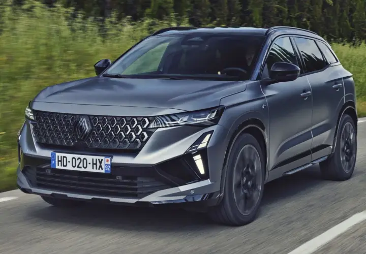 Nowy Austral Renault pędzi po drodze, otoczony zielenią.