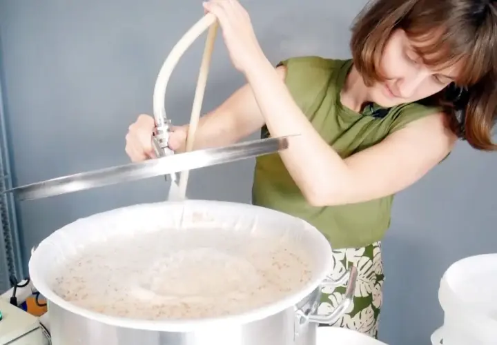Une femme prépare une recette d'IPA, versant un liquide dans une cuve de brassage.