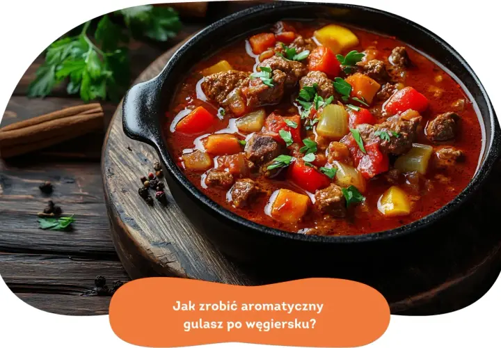 Aromatyczny gulasz po węgiersku w głębokiej misie, z kawałkami mięsa, papryki i ziemniaków. Obok przyprawy i ziół.
