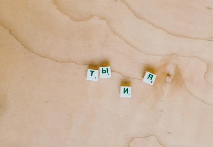 Litery "Ty" i "Я" na drewnianym tle. Zastanawiam się, jak ci minął dzień, co odpisać.