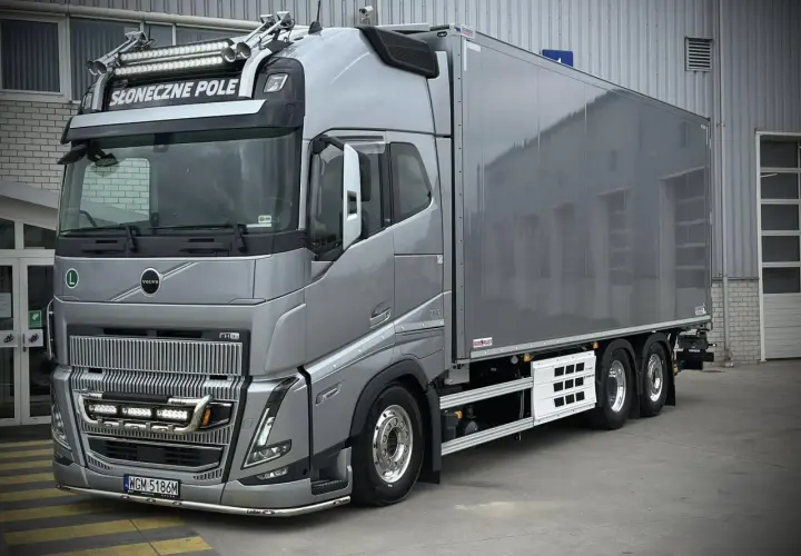 Srebrny Volvo FH16 z naczepą chłodniczą, ozdobiony dodatkowymi światłami i napisem "Słoneczne Pole".