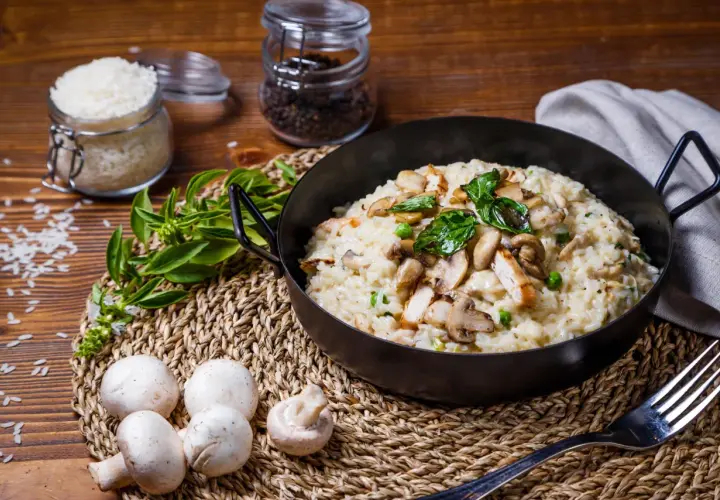 Un crémeux risotto poulet champignon, garni de basilic frais, prêt à être dégusté.