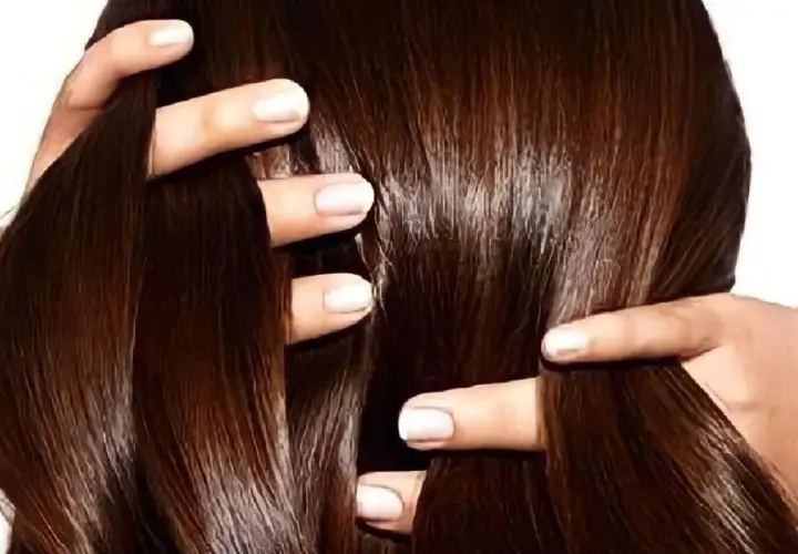 Manos peinando un cabello largo y sedoso de color chocolate.