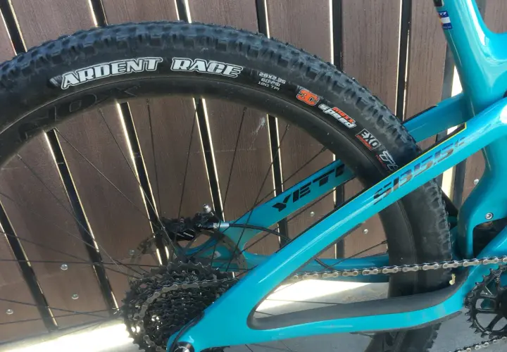 Close-up of a turquoise Yeti mountain bike rear wheel, featuring a Maxxis Ardent Race tire.