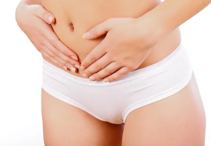 Mani che stringono delicatamente l'addome, evidenziando la zona pelvica. Un'immagine che evoca la delicatezza e le sfide delle perdite post parto.