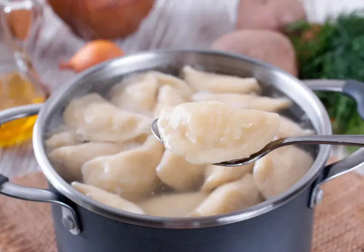 Gotowane pierogi w garnku, jeden na łyżce. Czy płukać pierogi po ugotowaniu? Zależy od przepisu!