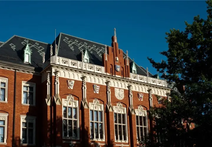 Elegancka fasada jednego z uniwersytetów w Krakowie, z charakterystycznymi detalami architektonicznymi i herbami.