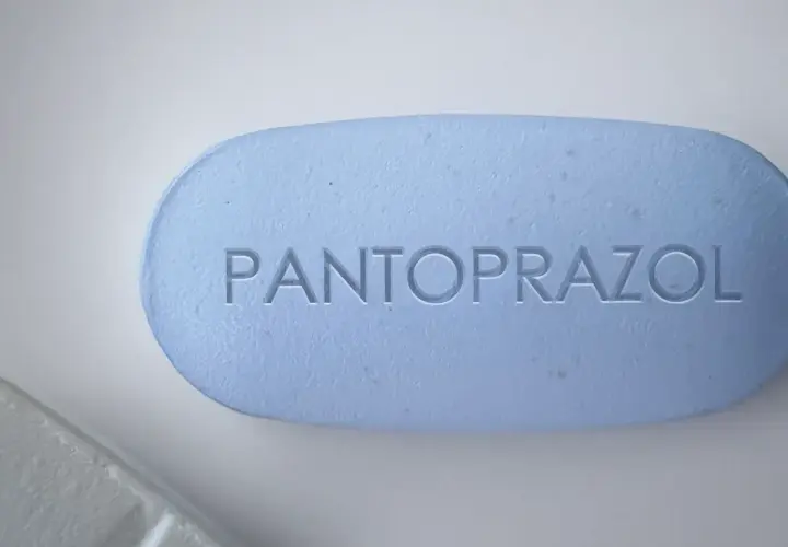 Ein hellblaues Pantoprazol-Tablett mit eingeprägtem Schriftzug. Manche Menschen nehmen Pantoprazol und Magnesium zusammen ein.