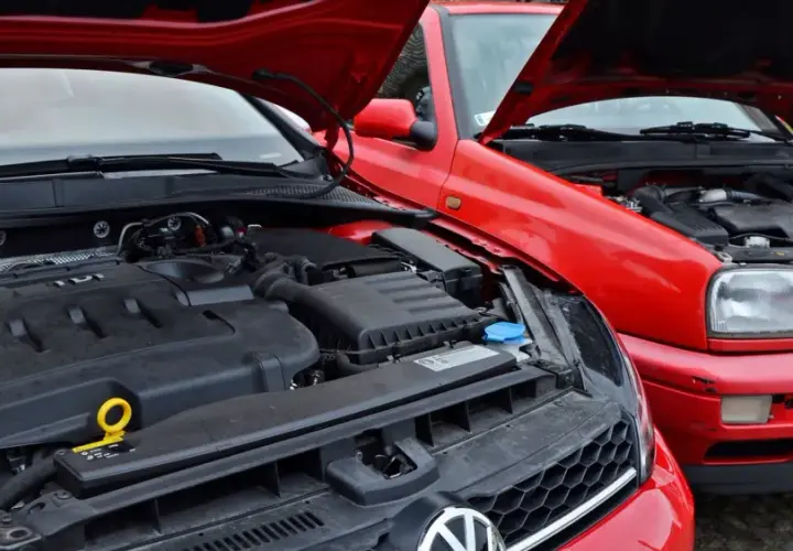 Dwa czerwone Volkswageny z otwartymi maskami, prezentujące swoje niezniszczalne silniki diesla TDI.