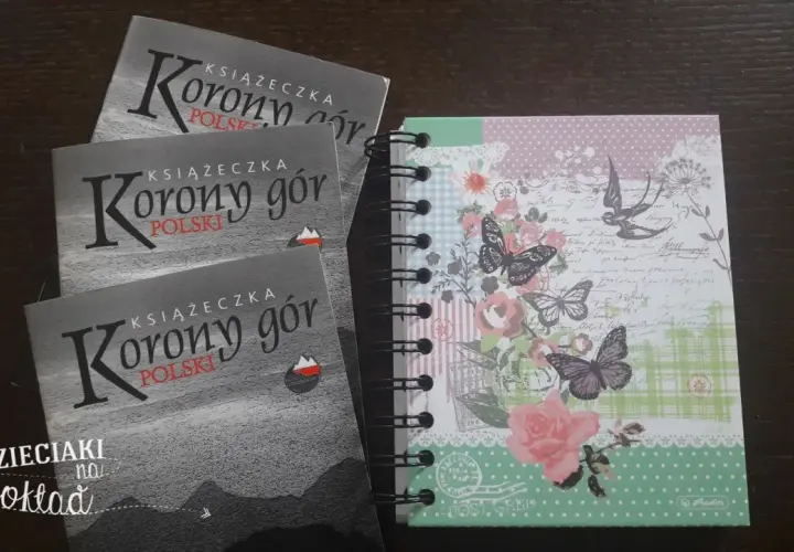 Trzy książeczki "Korony gór Polski" obok ozdobnego notesu w motyle i kwiaty. Idealne na górskie przygody!