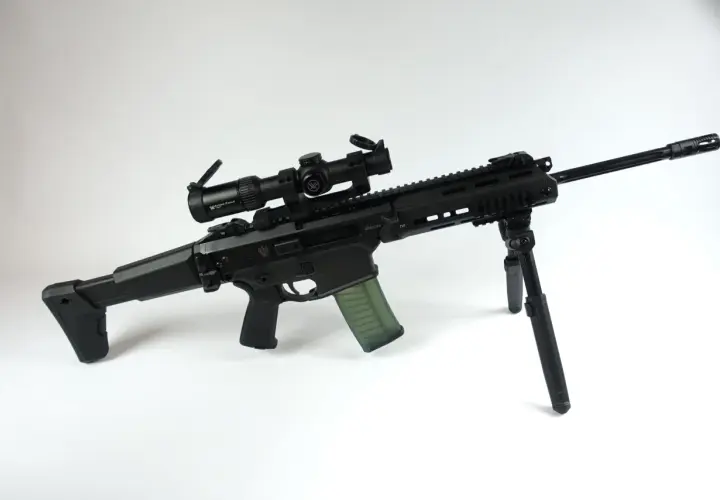 Czarny karabin z celownikiem optycznym Vortex Strike Eagle i zielonym magazynkiem. Kolimator do grota zapewnia precyzyjne celowanie.