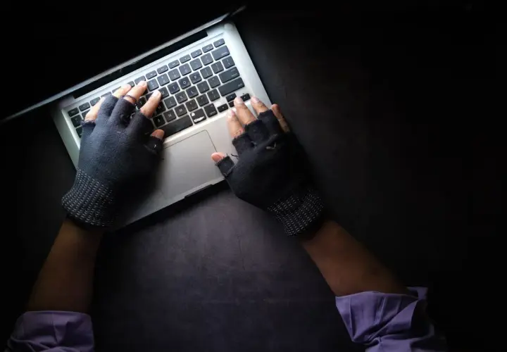 Ręce w rękawiczkach bez palców piszą na laptopie. To może być początek fascynujących studiów kryminalistycznych.
