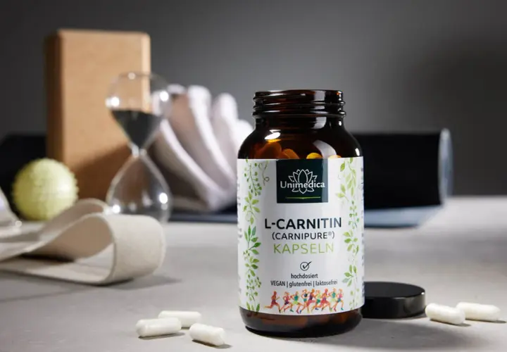 Flasche L-Carnitin Kapseln neben Yoga-Zubehör. Die richtige L-Carnitin Dosierung für dein Training.