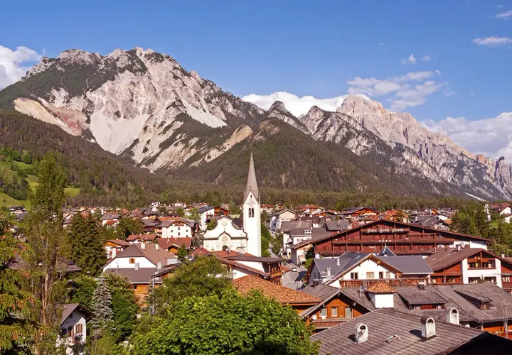 Charming Italy mountain towns nestled at the foot of majestic peaks. A church steeple rises above the rooftops.
