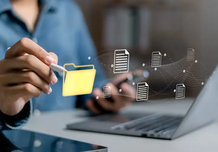 Main d'une personne utilisant un stylet pour interagir avec une icône de dossier jaune, symbolisant la digitalisation des processus et le flux de documents numériques.