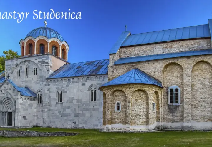 Kamienne mury i niebieskie dachy monastyru Studenica wznoszą się na tle zielonych wzgórz.