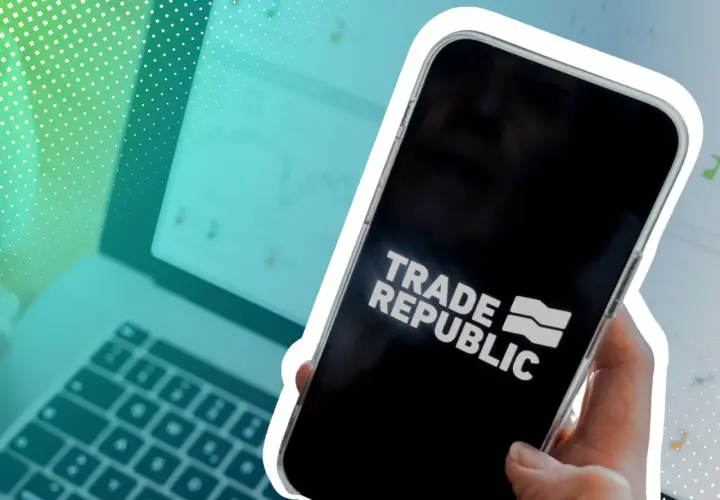 Hand hält Smartphone mit Trade Republic Logo. Im Hintergrund Laptop mit Charts. Ein trauriger Gedanke: Was passiert mit dem Depot bei einem Trade Republic Todesfall?