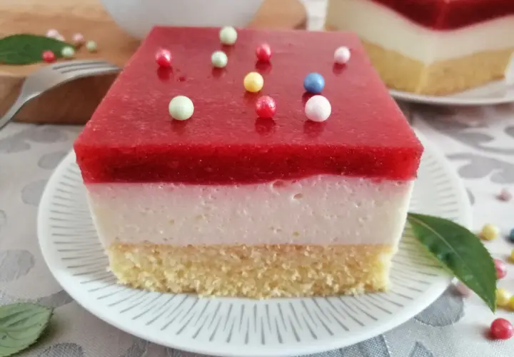 Pyszna żelka truskawkowa z mrożonych truskawek, z kremową warstwą i biszkoptem, ozdobiona kolorowymi kuleczkami.
