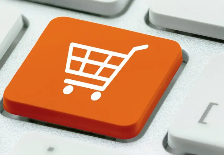 Pomarańczowy klawisz z ikoną koszyka na zakupy. To symbol e-commerce co to jest, czyli handlu elektronicznego.