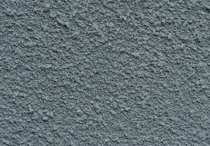 Dettaglio di pittura sabbiata grigia, con texture granulosa. Valutare i pro e contro di questo tipo di finitura per esterni.