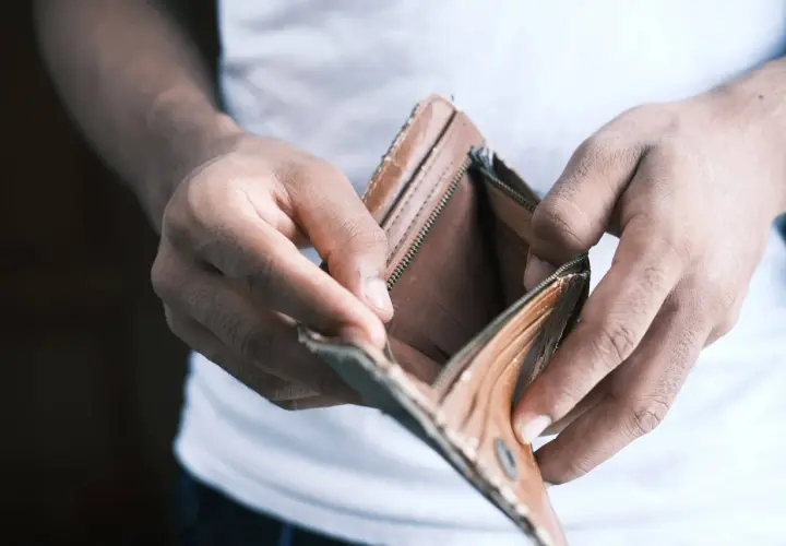Mani che aprono un portafoglio vuoto, simbolo di problemi economici in famiglia.
