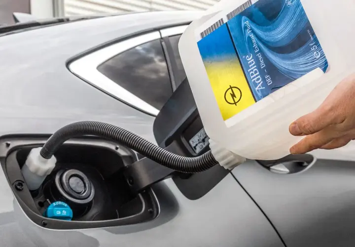 Rellenando el depósito de AdBlue de un coche. La etiqueta indica "AdBlue DEF - Diesel Exhaust Fluid". Saber cuanto dura el AdBlue es clave para evitar paradas.