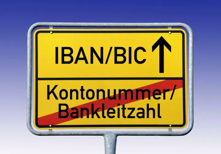 Gelbes Ortsschild mit "IBAN/BIC" und Pfeil nach oben. Darunter "Kontonummer/Bankleitzahl" durchgestrichen.