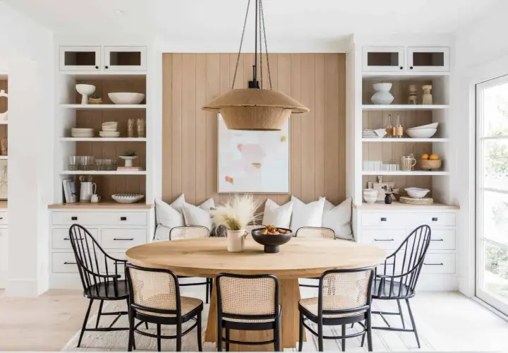 Chic dining table decor ideas: a round wood table with cane chairs, a woven pendant light, and built-in shelving.