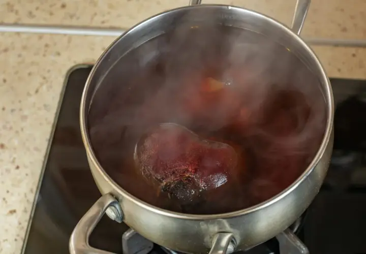 Cuisson de betteraves rouges dans une casserole d'eau bouillante. La vapeur s'échappe de la cocotte.