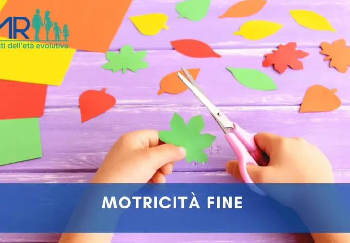 Mani di bambino che ritagliano forme di foglie colorate con forbici rosa, un'attività per sviluppare la motricità fine.