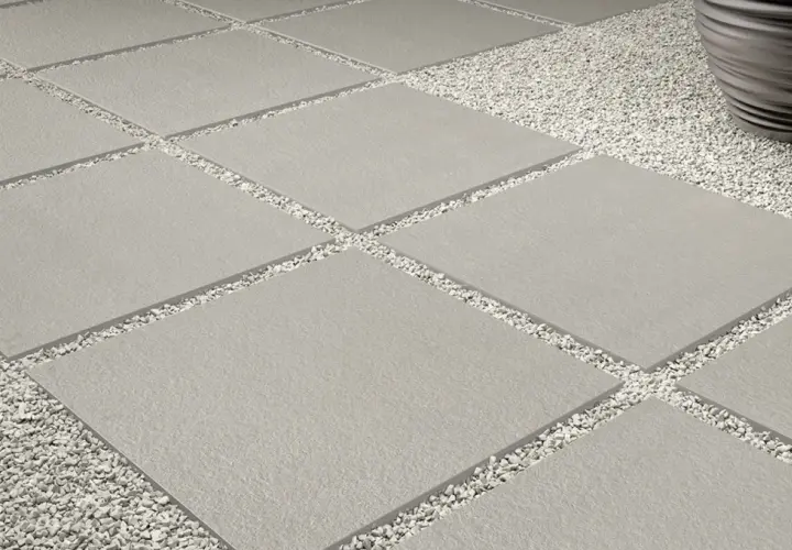 Posa a secco su ghiaia: lastre quadrate grigie alternate a ghiaia bianca, creando un percorso moderno e pulito.
