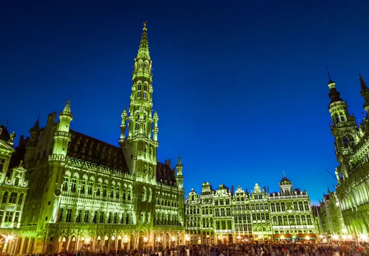 Wieczorem na Grand Place w Brukseli, oświetlone ratusz i kamienice tworzą magiczny widok.