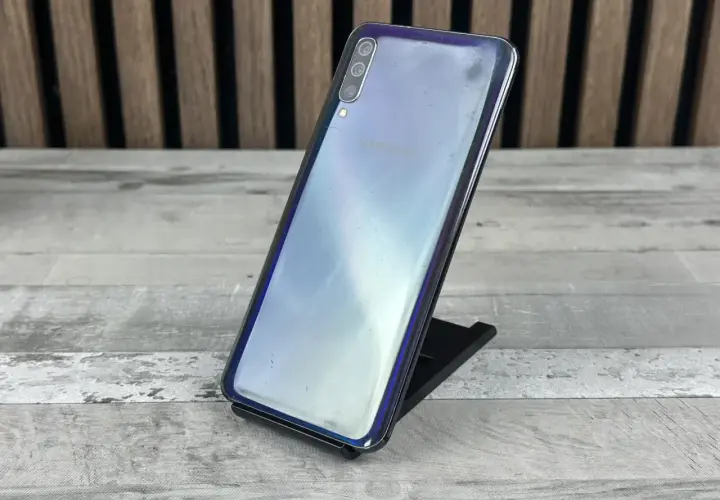 Telefon Samsung Galaxy A50 na czarnym stojaku, z widocznym logo Samsung. Sprawdź aktualną samsung galaxy a50 cena.