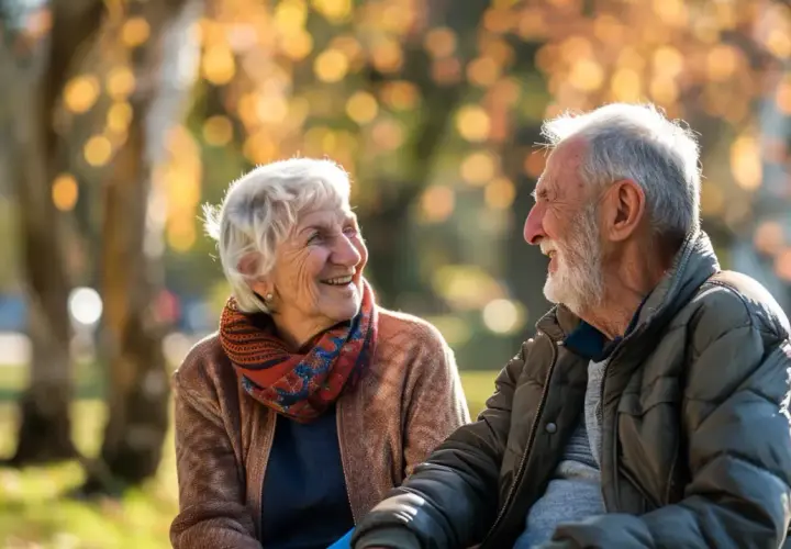 Uśmiechnięta para seniorów cieszy się jesiennym dniem w parku. Dobre samopoczucie zawdzięczają pewnie zdrowej diecie i codziennej multiwitaminie.