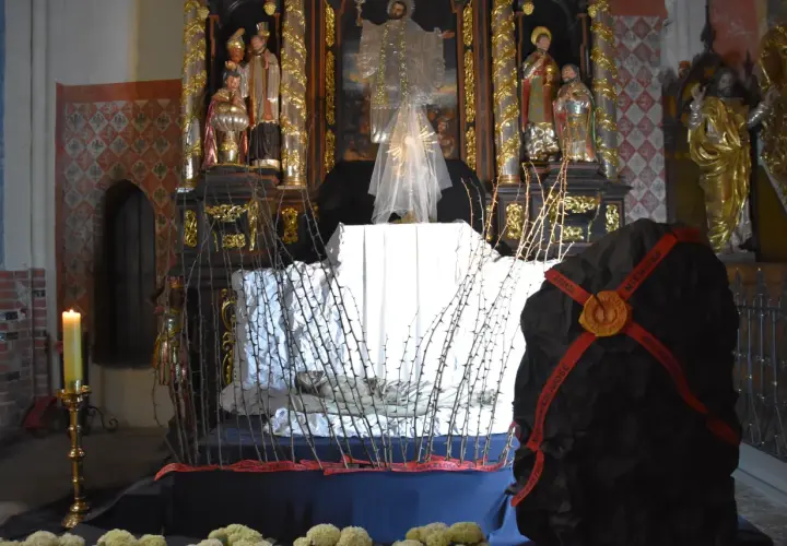Ołtarz w kościele z grobem Chrystusa, ozdobiony ciernistymi gałęziami i świecą.