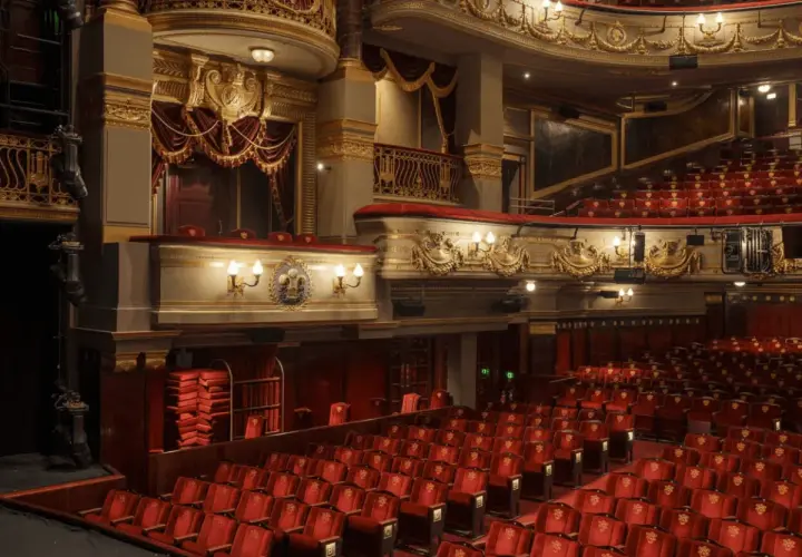 Luksusowe wnętrze teatru z czerwonymi fotelami i złotymi zdobieniami. Zastanawiasz się, ile trwa przedstawienie w teatrze?