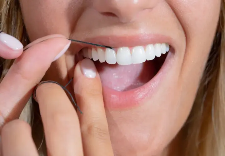 Dita curate usano filo interdentale abrasivo per pulire i denti bianchi e brillanti.