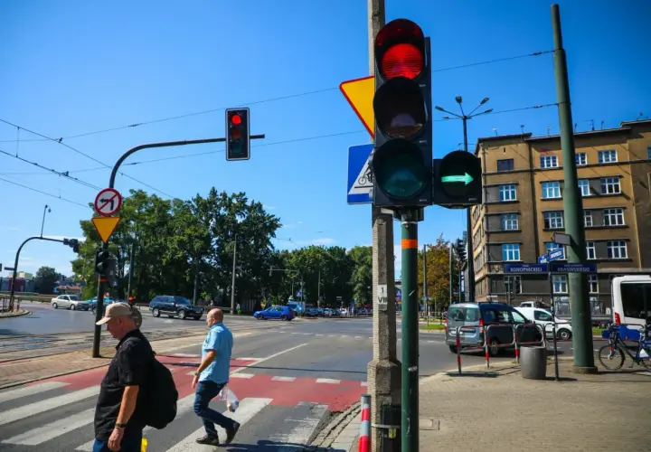 Sygnalizator S2 z zieloną strzałką w prawo, czerwonym światłem u góry. Ludzie przechodzą przez pasy.