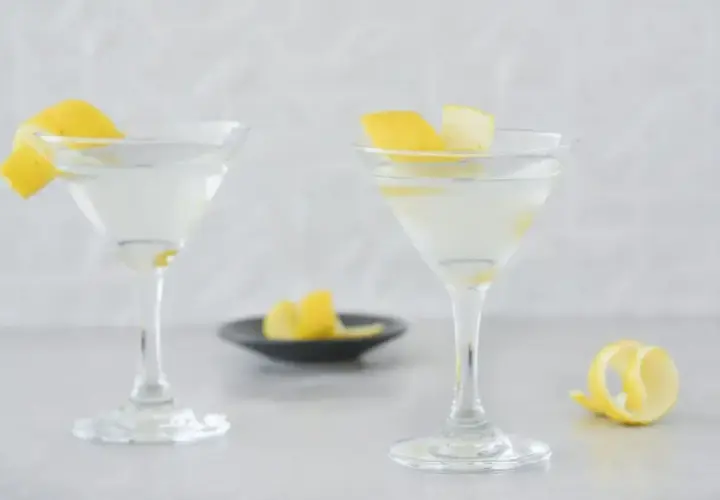 Dwa eleganckie drinki z martini, ozdobione skórką cytrynową, czekają na spróbowanie.
