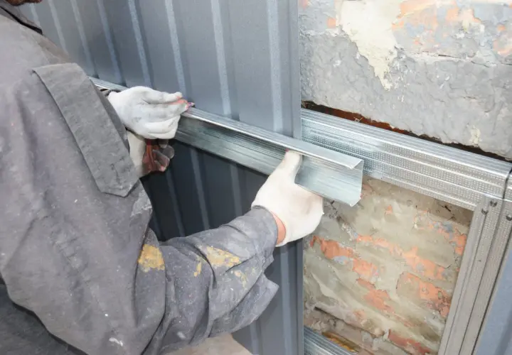 Arbeiter montiert Metallprofile für die Abdichtung des Hauses.
