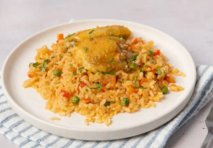 Plato de arroz con pollo, zanahorias, guisantes y pimientos rojos. Una deliciosa receta de arroz con pollo lista para servir.