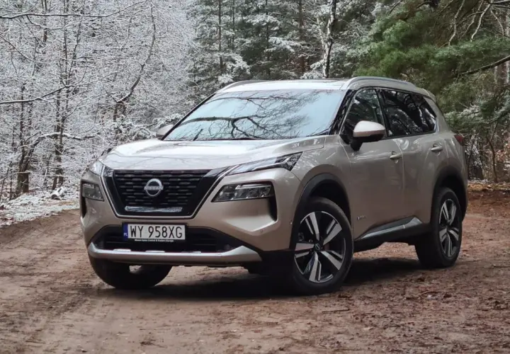 Złoty Nissan X-Trail na leśnej drodze zimą. Wiele osób szuka nissan x trail opinie, ten SUV świetnie radzi sobie w trudnych warunkach.