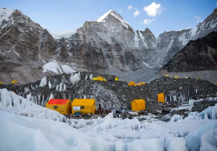Obóz u podnóża Mount Everest, gdzie **mount everest wysokość** jest wyzwaniem. Żółte namioty na lodowcu, w tle majestatyczne, skaliste szczyty.