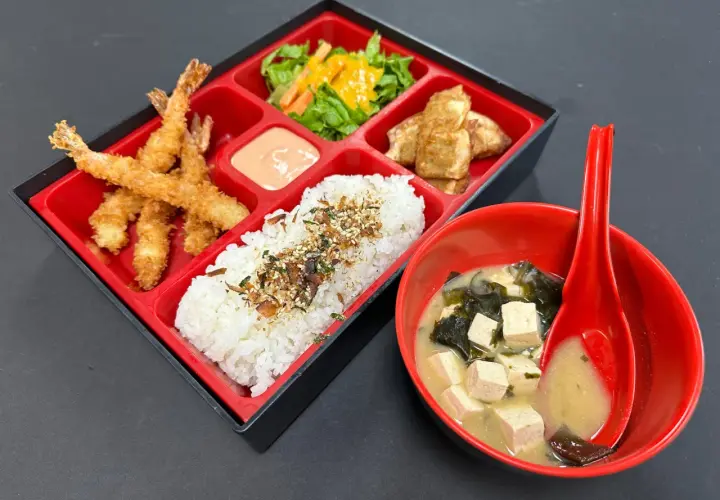 A delicious shrimp bento box with crispy fried shrimp, rice, salad, and tofu, served with miso soup.