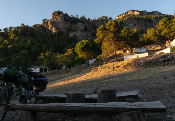 Bicicleta cargada para aventura, lista para explorar el GR 247 en bici. Paisaje montañoso al atardecer.